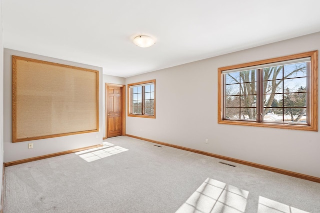 empty room featuring visible vents, baseboards, and light colored carpet