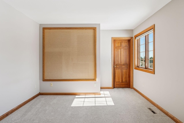 spare room with baseboards, visible vents, and light carpet