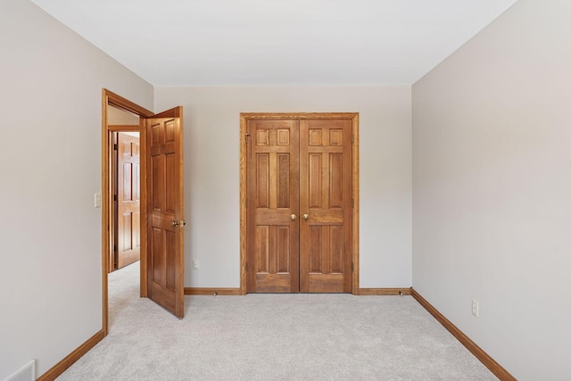 unfurnished bedroom featuring visible vents, light carpet, and baseboards