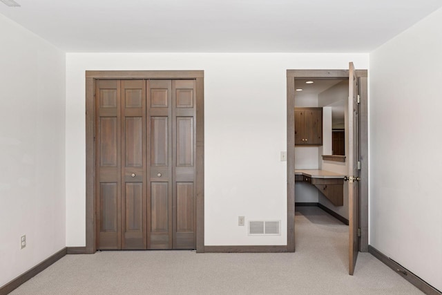 unfurnished bedroom featuring baseboards, visible vents, a closet, and light carpet