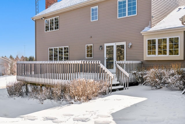 snow covered rear of property with a chimney and a deck