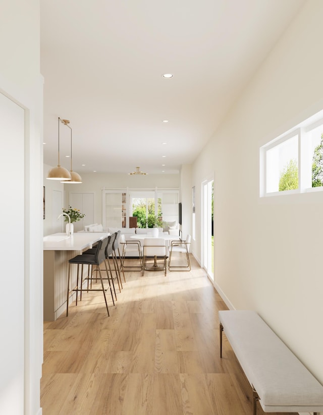 corridor featuring recessed lighting, a healthy amount of sunlight, and light wood-style flooring