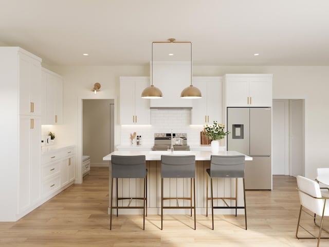 kitchen featuring stainless steel range, white cabinets, an island with sink, light countertops, and built in fridge