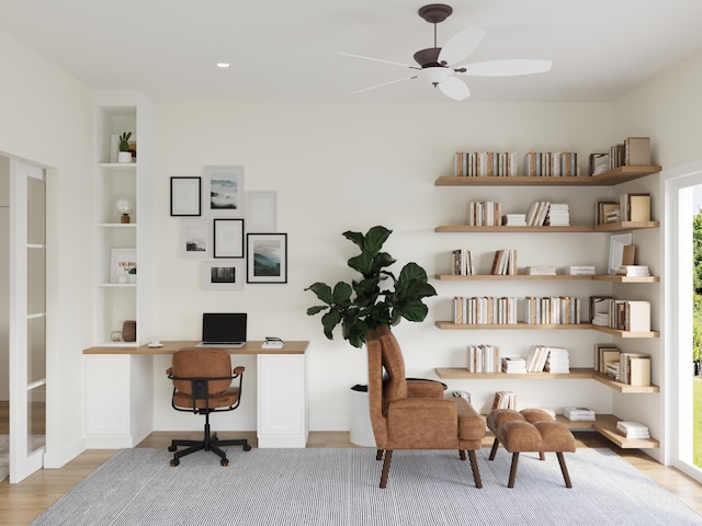 office area with built in shelves, light wood-type flooring, ceiling fan, and built in desk