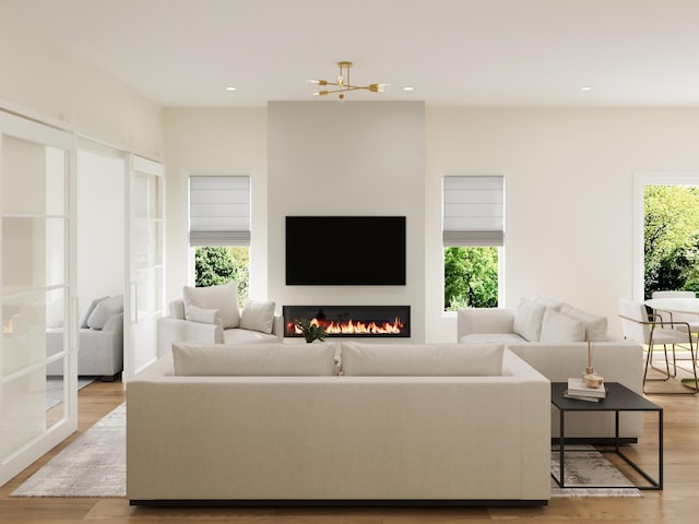 living area featuring light wood finished floors, a glass covered fireplace, and recessed lighting