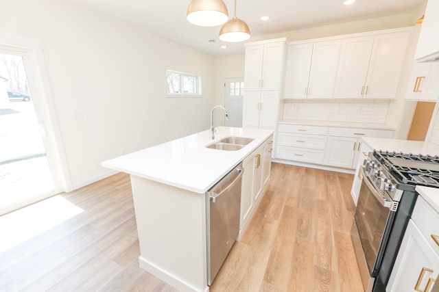 kitchen with tasteful backsplash, a sink, light wood-style floors, stainless steel appliances, and light countertops