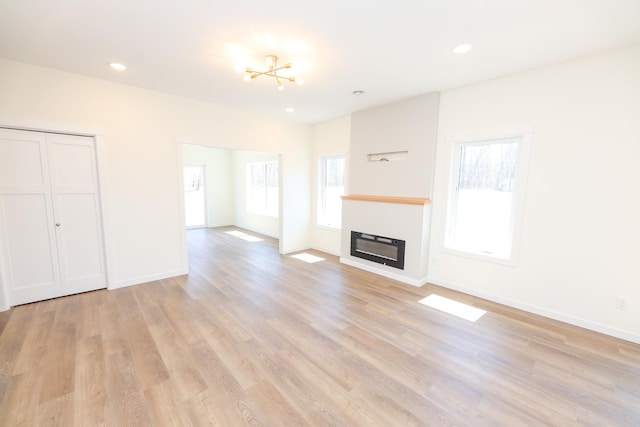 unfurnished living room featuring a chandelier, recessed lighting, light wood finished floors, and baseboards