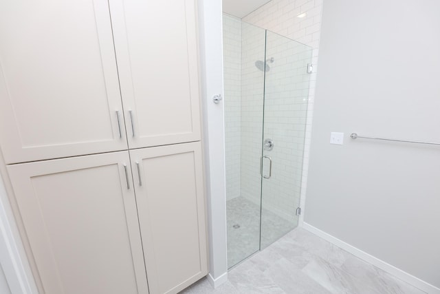 bathroom featuring a shower stall, marble finish floor, and baseboards