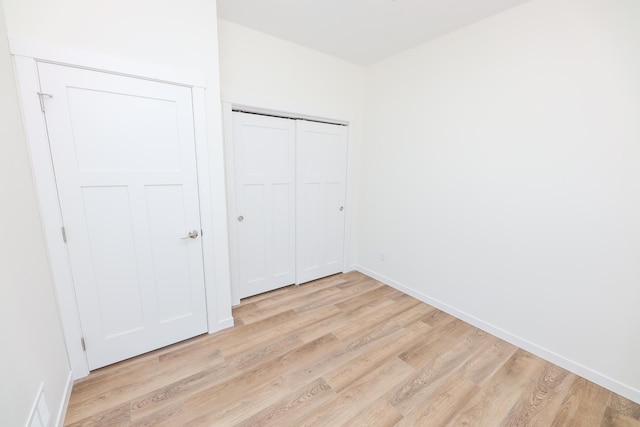unfurnished bedroom with baseboards, visible vents, light wood-style floors, and a closet