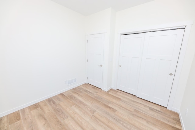 unfurnished bedroom with light wood-style floors, a closet, visible vents, and baseboards