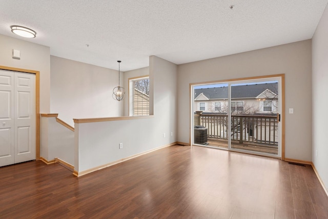 empty room with baseboards, an inviting chandelier, and wood finished floors