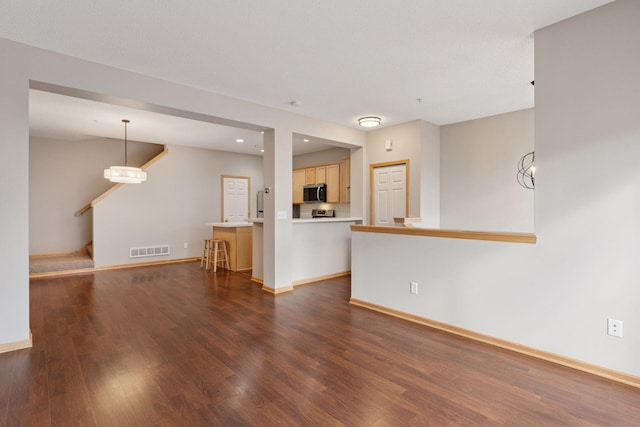 unfurnished living room with stairs, dark wood-type flooring, visible vents, and baseboards