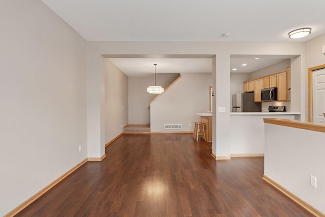 unfurnished living room featuring dark wood finished floors, visible vents, and baseboards