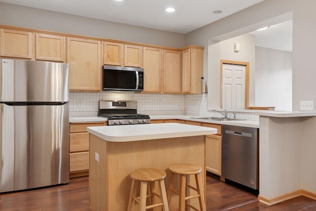 kitchen featuring stainless steel appliances, a sink, backsplash, and light brown cabinetry