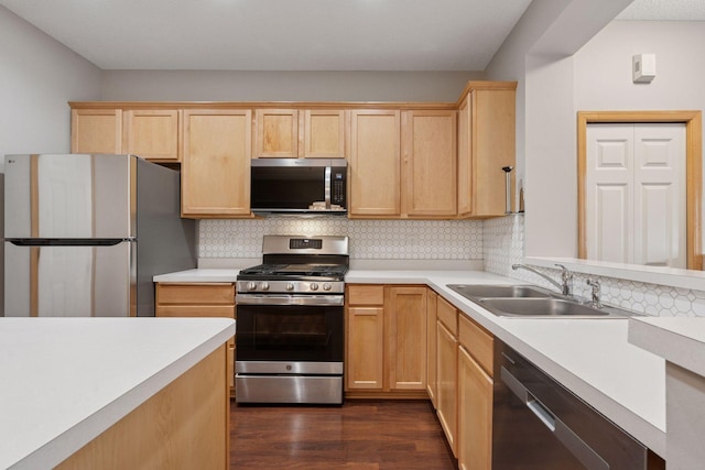 kitchen featuring stainless steel appliances, light brown cabinets, and a sink