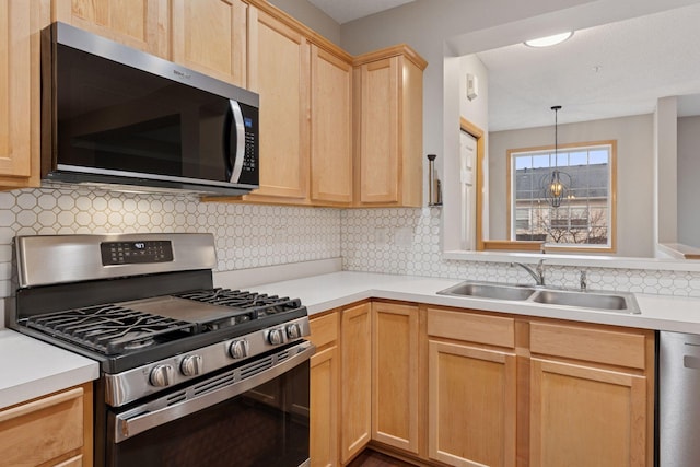 kitchen featuring light brown cabinets, light countertops, appliances with stainless steel finishes, and a sink