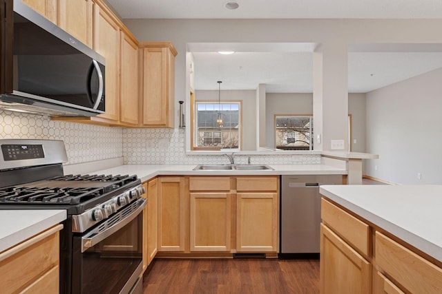 kitchen with stainless steel appliances, a sink, light countertops, dark wood-style floors, and light brown cabinetry