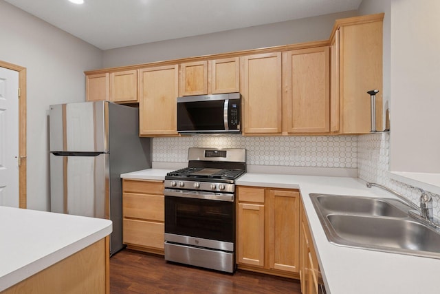 kitchen featuring appliances with stainless steel finishes, a sink, decorative backsplash, and light brown cabinetry