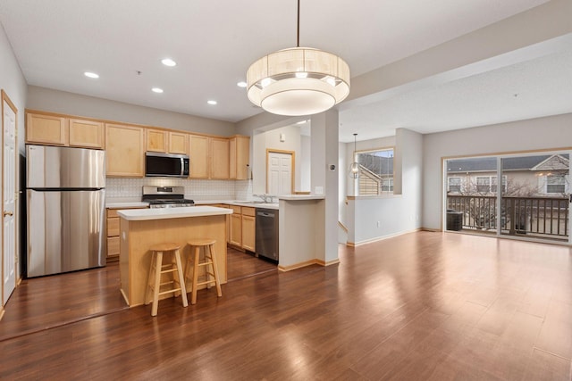 kitchen featuring light brown cabinets, stainless steel appliances, light countertops, decorative backsplash, and a center island