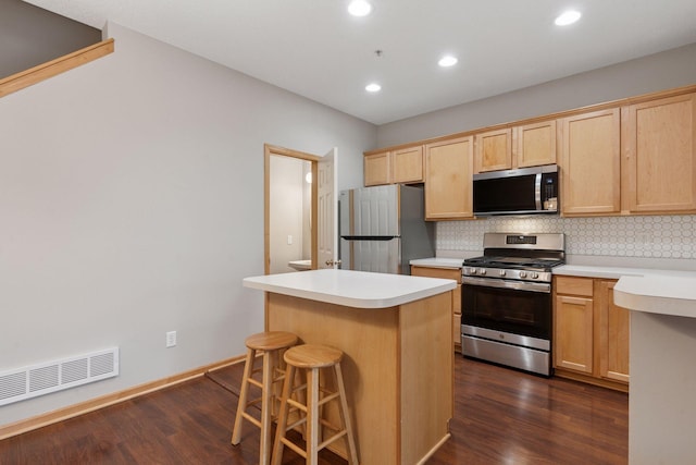 kitchen featuring tasteful backsplash, visible vents, a kitchen island, stainless steel appliances, and light brown cabinetry