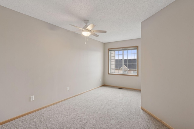 carpeted spare room featuring ceiling fan, visible vents, baseboards, and a textured ceiling