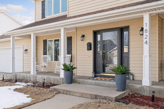 view of exterior entry with a garage and covered porch