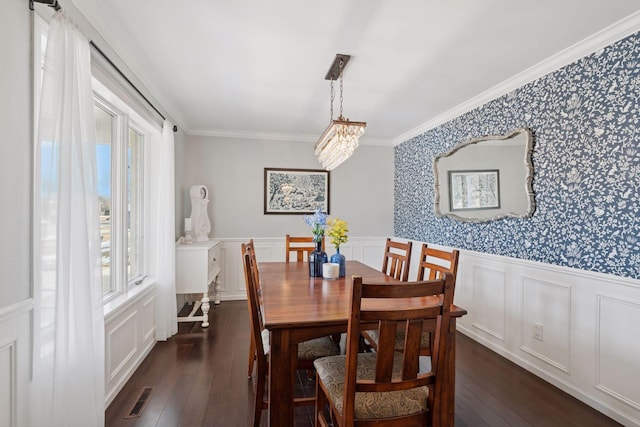 dining space featuring visible vents, ornamental molding, wainscoting, wallpapered walls, and dark wood-style flooring