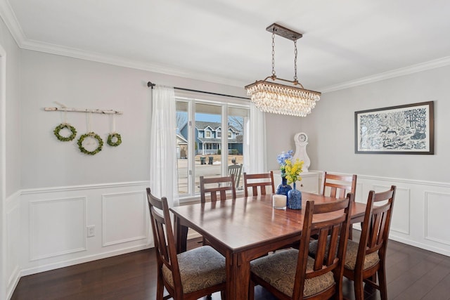 dining area featuring a notable chandelier, a wainscoted wall, crown molding, and dark wood-type flooring