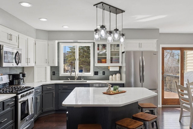 kitchen with a breakfast bar area, a sink, stainless steel appliances, white cabinets, and backsplash