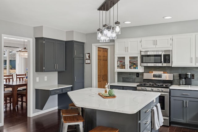 kitchen featuring light stone counters, gray cabinetry, appliances with stainless steel finishes, tasteful backsplash, and a center island