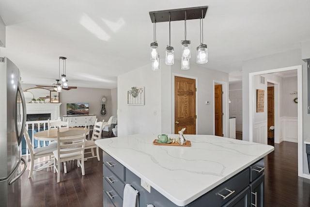 kitchen with ceiling fan, open floor plan, a fireplace, freestanding refrigerator, and dark wood-style flooring