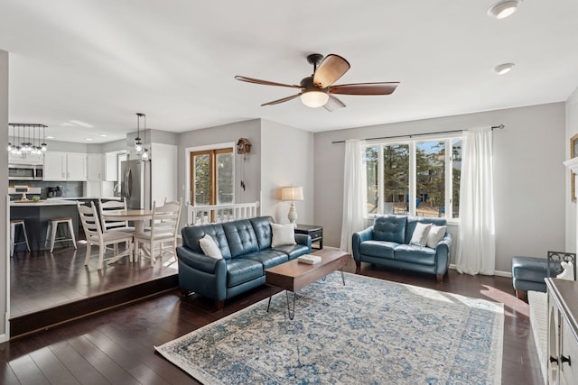 living room with baseboards, dark wood-type flooring, and a ceiling fan