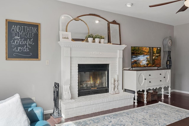 details featuring a fireplace, a ceiling fan, baseboards, and wood finished floors