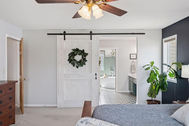 bedroom with a barn door, light colored carpet, and a textured ceiling