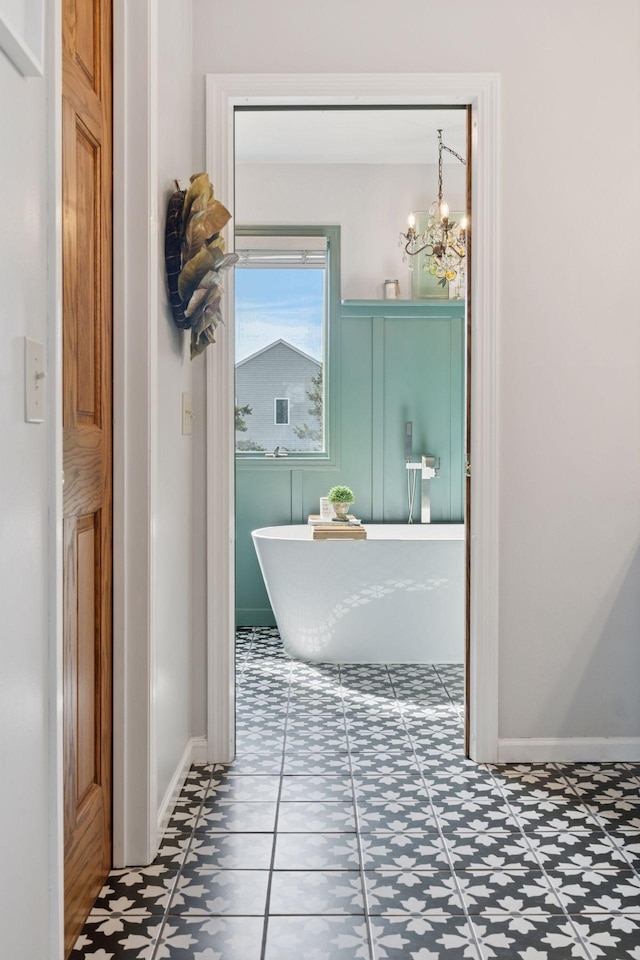 full bathroom featuring baseboards, a soaking tub, and a chandelier