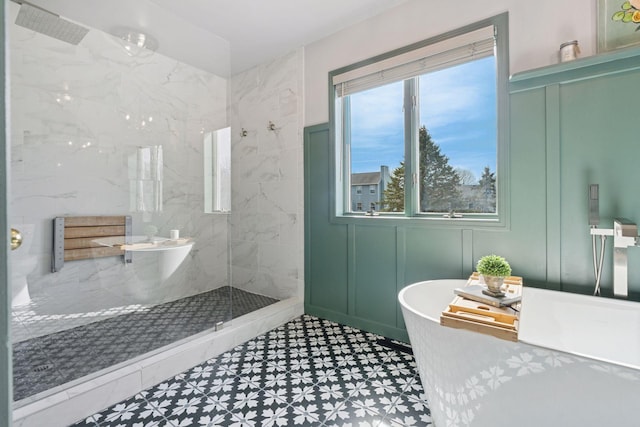 bathroom featuring a marble finish shower, a freestanding bath, and a decorative wall