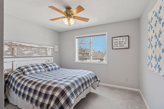 carpeted bedroom featuring ceiling fan, baseboards, and a textured ceiling