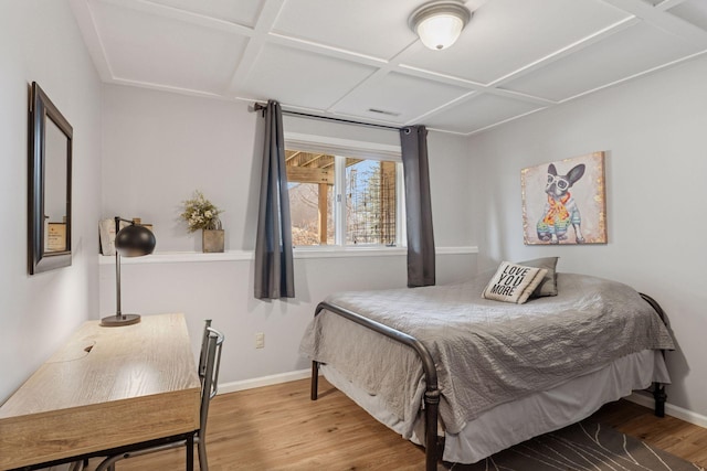 bedroom with coffered ceiling, baseboards, and wood finished floors