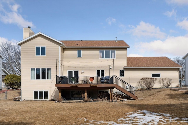 rear view of property with stairway, a wooden deck, roof with shingles, a lawn, and a chimney