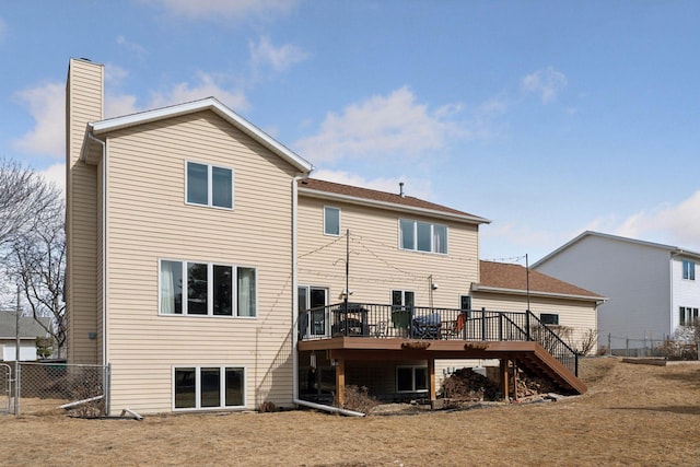 rear view of property with stairs, a wooden deck, fence, and a chimney