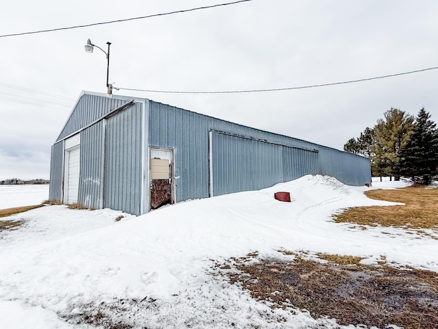 snow covered structure featuring an outbuilding and an outdoor structure