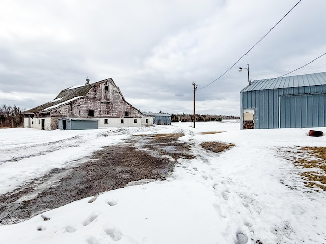 18863 State Highway 65, Goodland Twp, MN 55742 - snowy yard with a garage, an outbuilding, and a barn