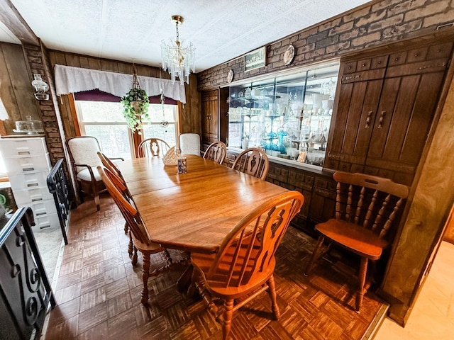 18863 State Highway 65, Goodland Twp, MN 55742 - dining space with an inviting chandelier, brick wall, a textured ceiling, and wood walls