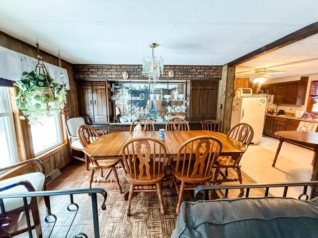 18863 State Highway 65, Goodland Twp, MN 55742 - dining area with brick wall, visible vents, a textured ceiling, and ceiling fan with notable chandelier