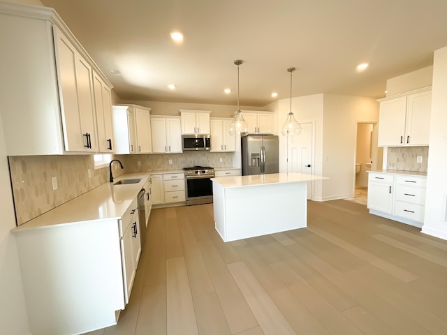 kitchen featuring recessed lighting, a sink, light countertops, appliances with stainless steel finishes, and a center island