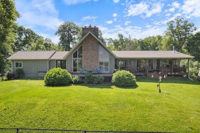 back of property with a chimney and a lawn