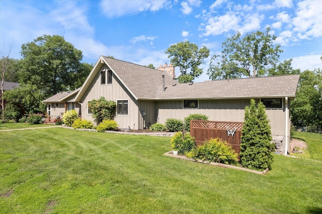 exterior space with a chimney, a front lawn, and roof with shingles