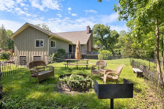 back of property with a fenced backyard, a chimney, and a lawn