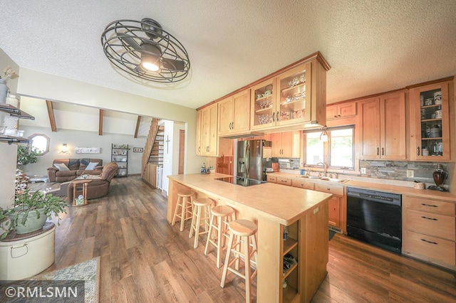 kitchen with a kitchen breakfast bar, open floor plan, light countertops, black appliances, and a sink