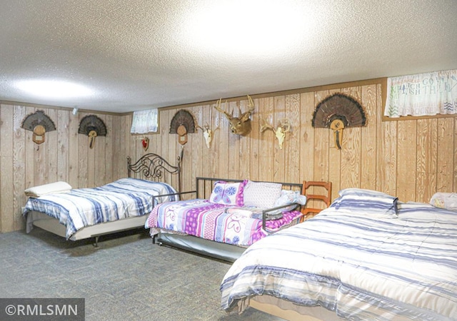 bedroom featuring carpet floors, wood walls, and a textured ceiling